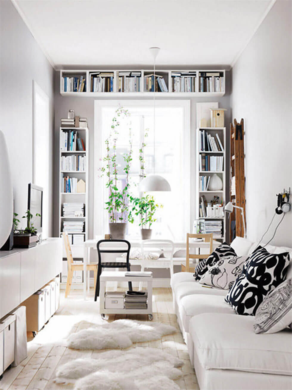 Small white living room with a white sofa, rug and bookshelves