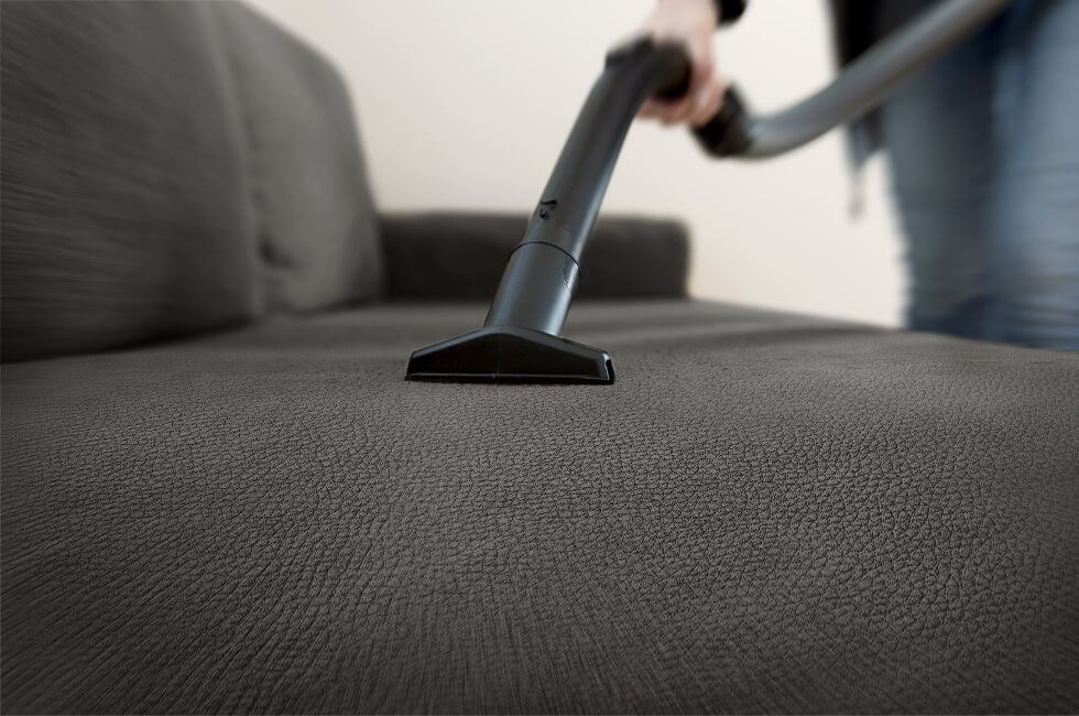 Vacuuming a faux leather sofa in the living room