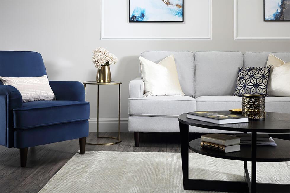  Modern living room with grey fabric sofa, dark blue armchair, white cushions and feature wall