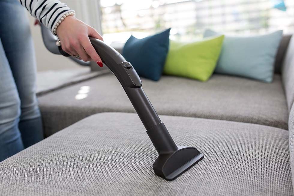 using a handheld vacuum cleaner to clean your fabric sofa