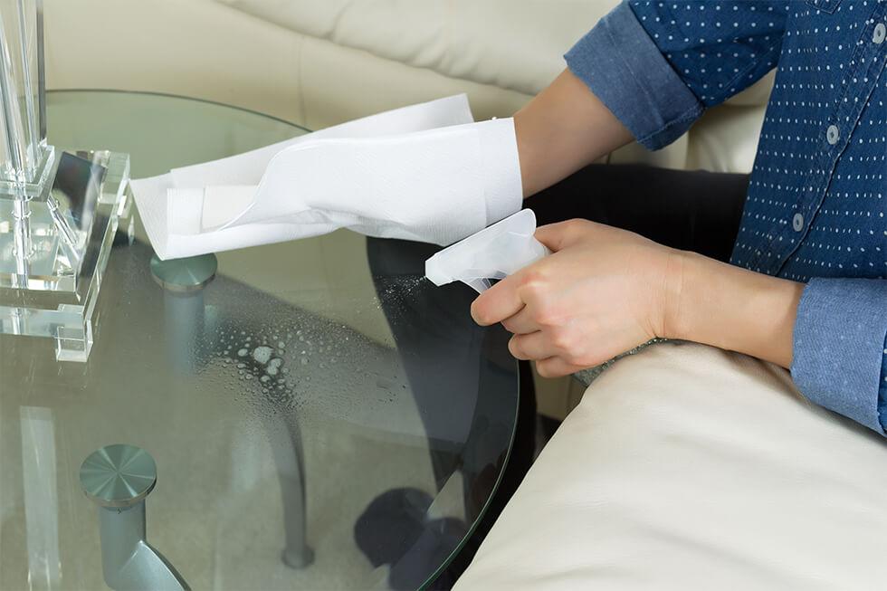 The process of cleaning a glass table with a cloth and cleaning spray