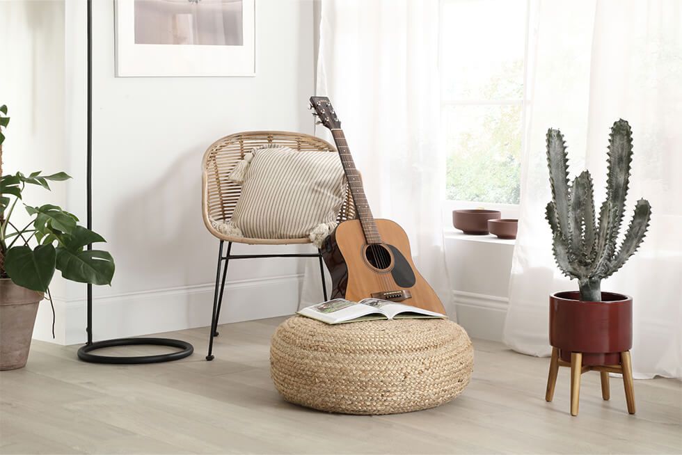 A chill out corner with a rattan armchair, guitar and potted plants