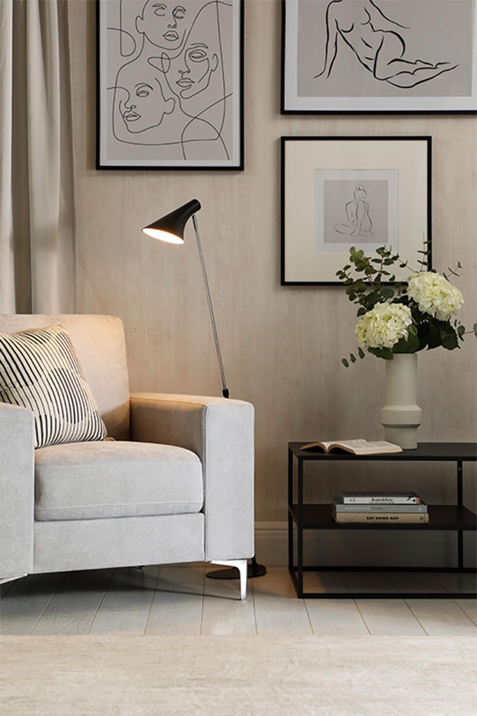 A chill out corner in a modern living room with a grey armchair against a gallery wall