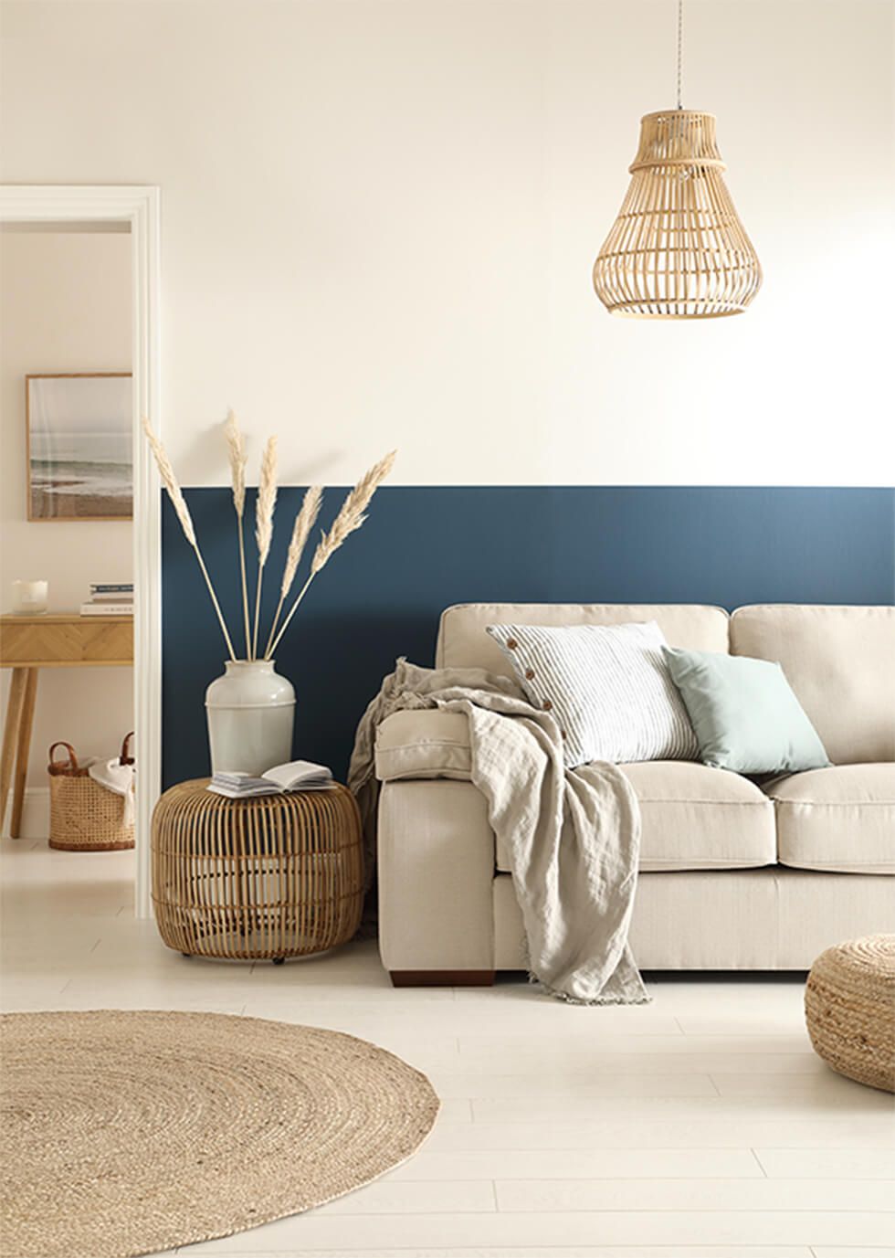 A calming living room with a half painted blue wall and linen sofa