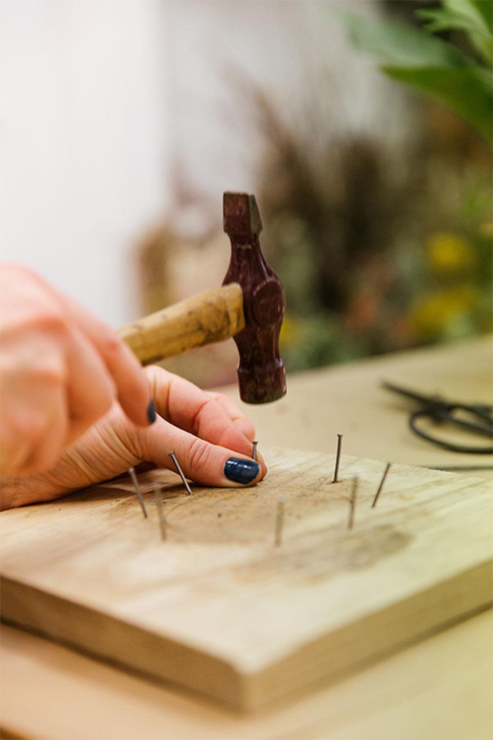 Hammering 8 nails along the pencilled outline of the wooden boards