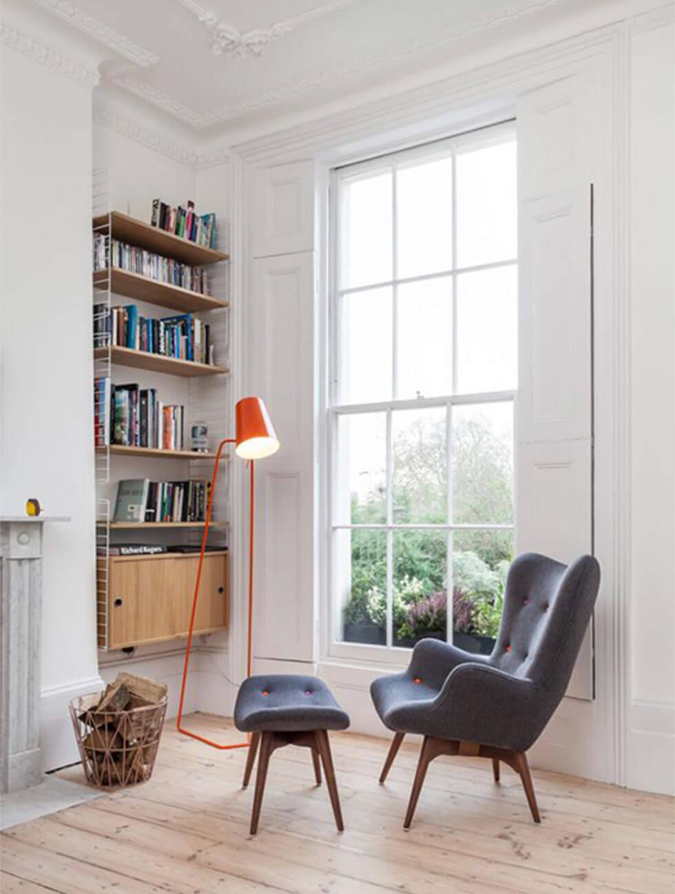 grey padded armchair with ottoman with orange lamp