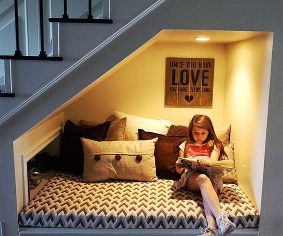 child relaxing in reading nook under the stairs