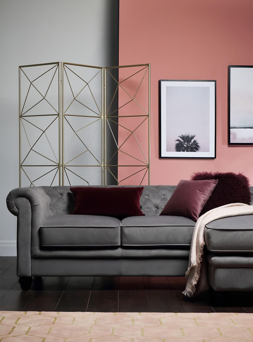 A grey velvet Chesterfield L-shape corner sofa dressed with 3 cushions and a throw