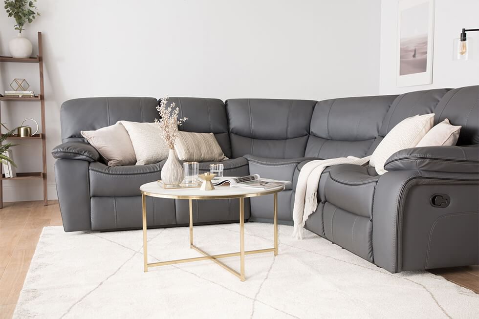 A grey leather recliner corner sofa with elegant neutral cushions in a modern living room