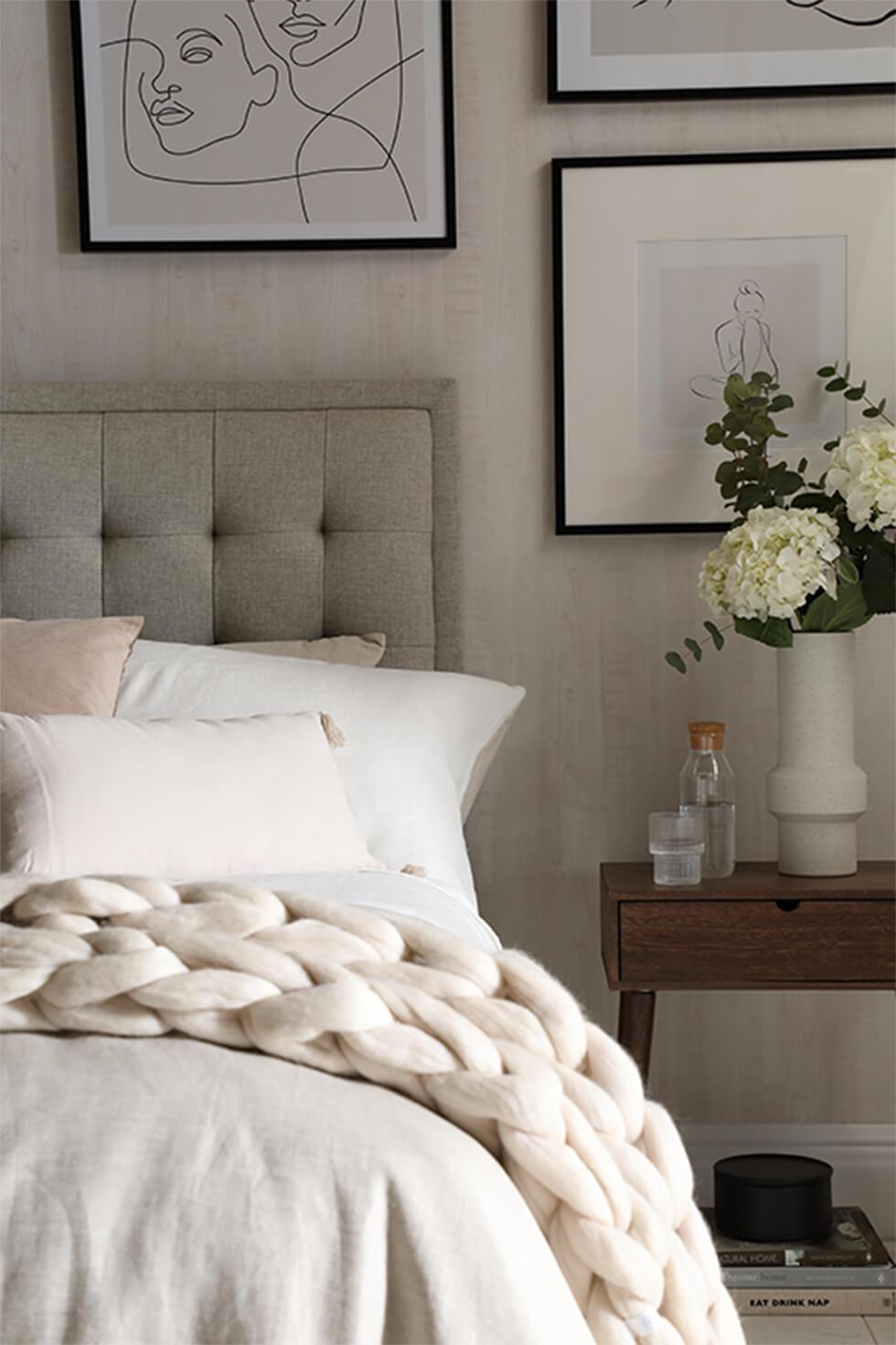 Neutral bedroom with white bedspread and throw with tufted headboard