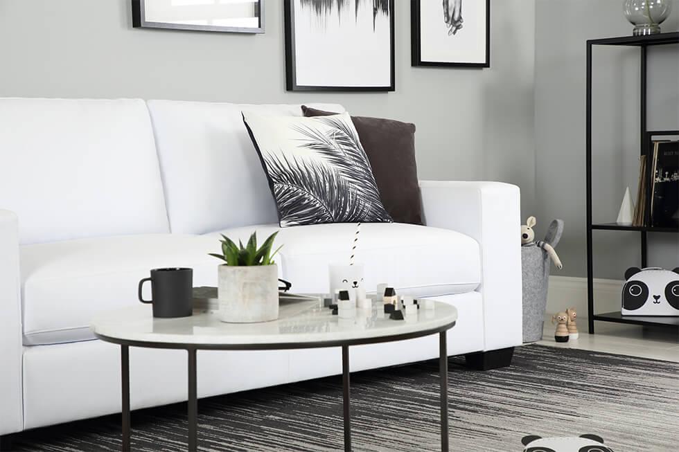 Bright white living room with white leather sofa and black decor