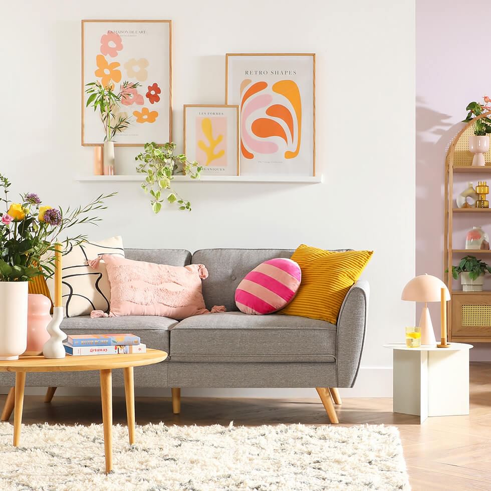 A light grey sofa with mustard yellow and blush pink cushions
