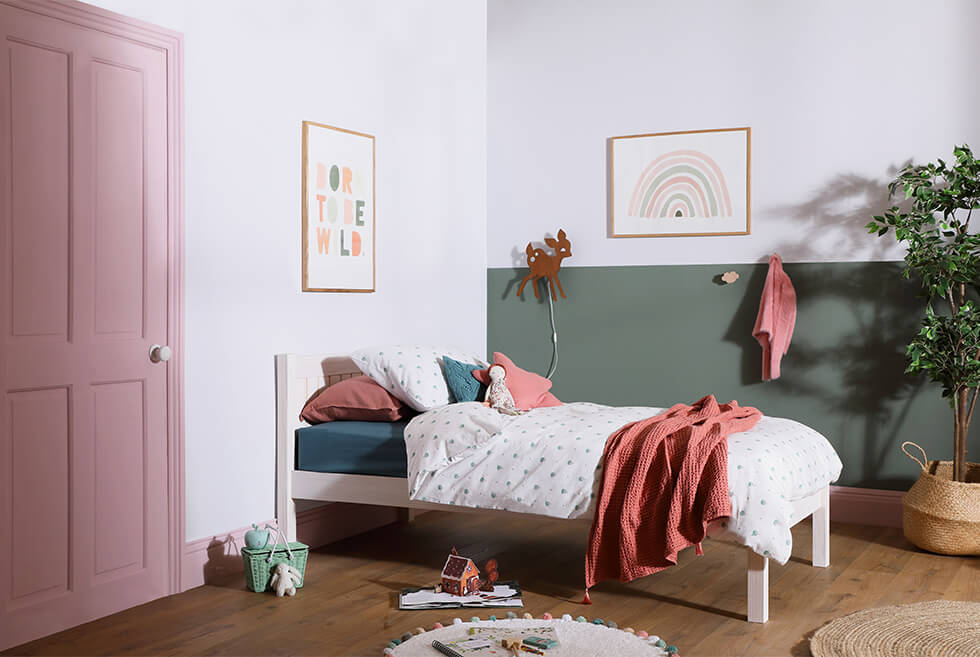 Children's bedroom with a white and green half-painted wall and pink door