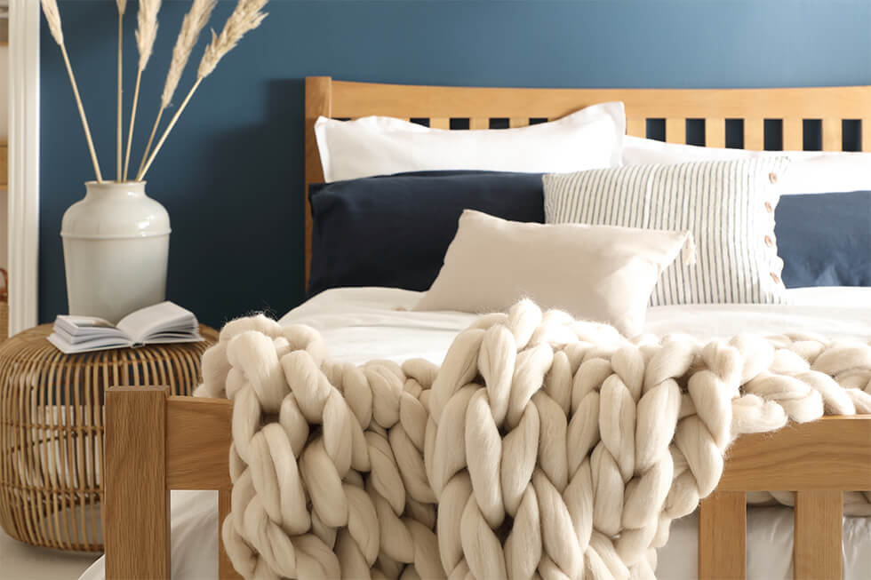 Beachy bedroom with wooden bed, white sheets and rattan decor