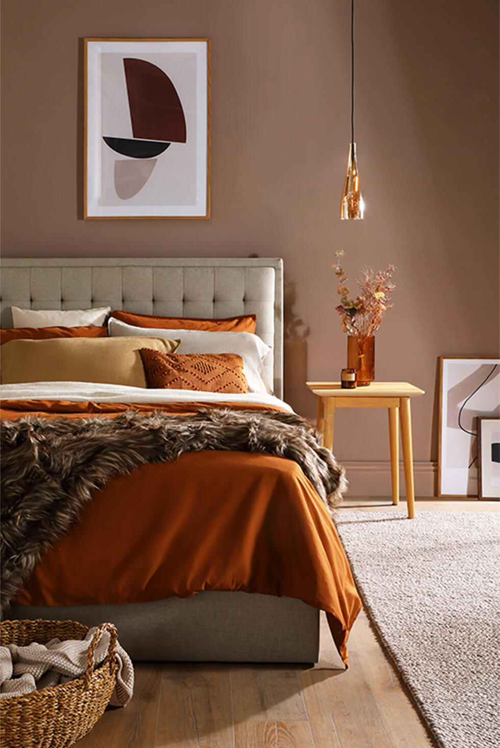 Dramatic neutral bedroom with a fabric bed, and brown and gold accents