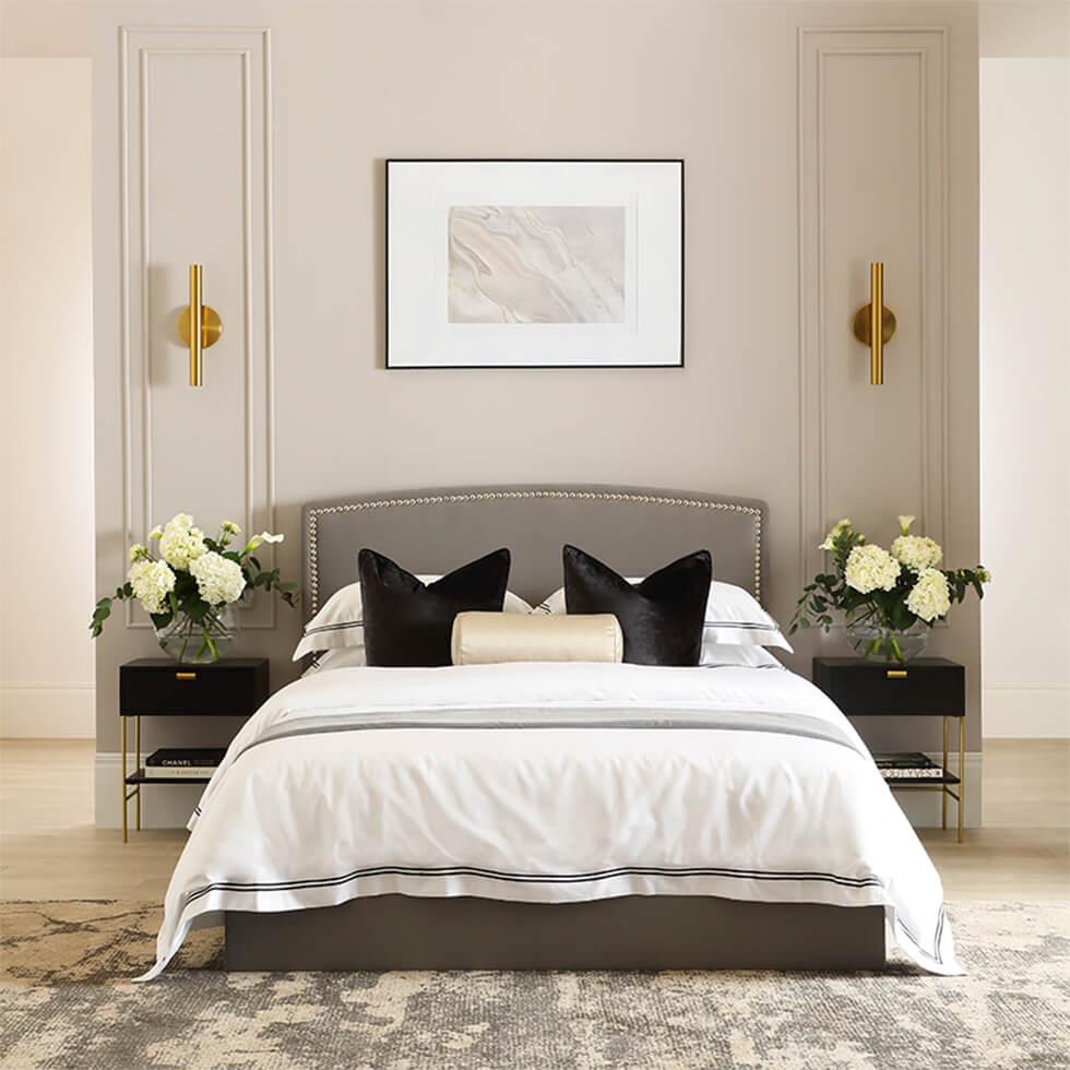 Neutral bedroom with grey fabric bed, framed art and fresh flowers