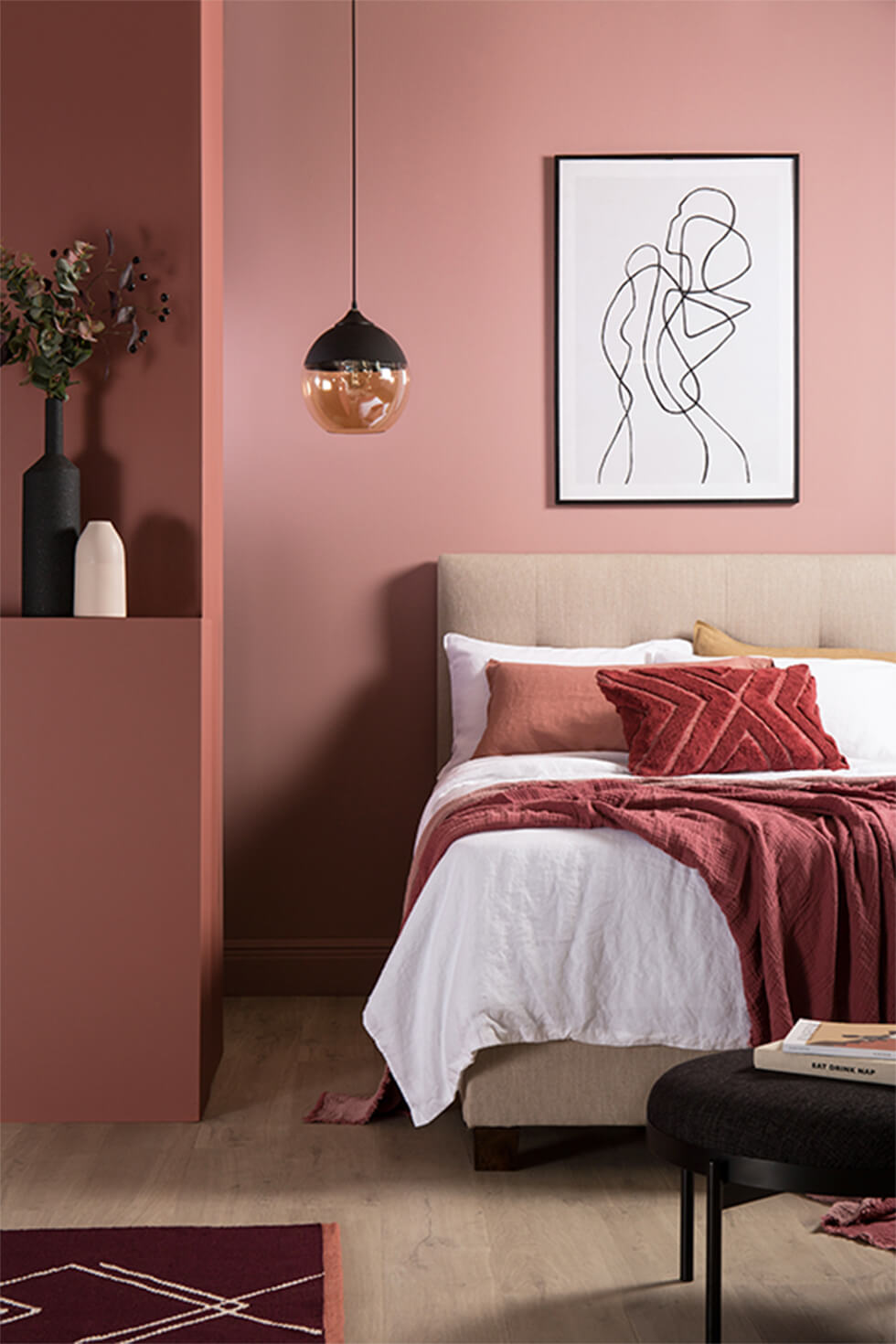 Pink bedroom with fabric bed, glass pendant lamp and terracotta accents