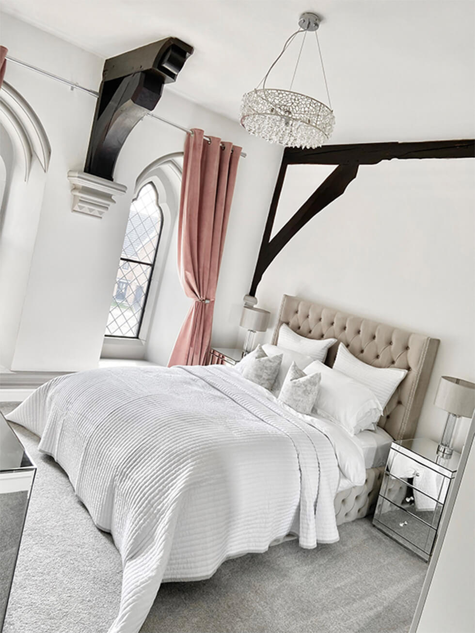 grey bedroom with cosy bedding and luxurious chandelier