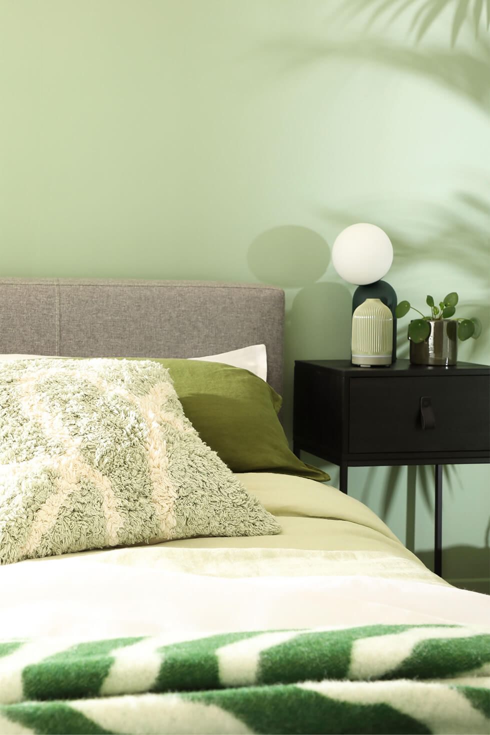 Close up of green bedroom with grey fabric bed