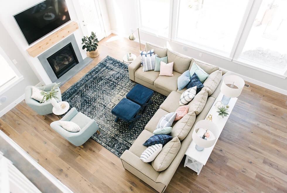 A wide view of a beige corner sofa facing a fireplace and with a side table at the back.