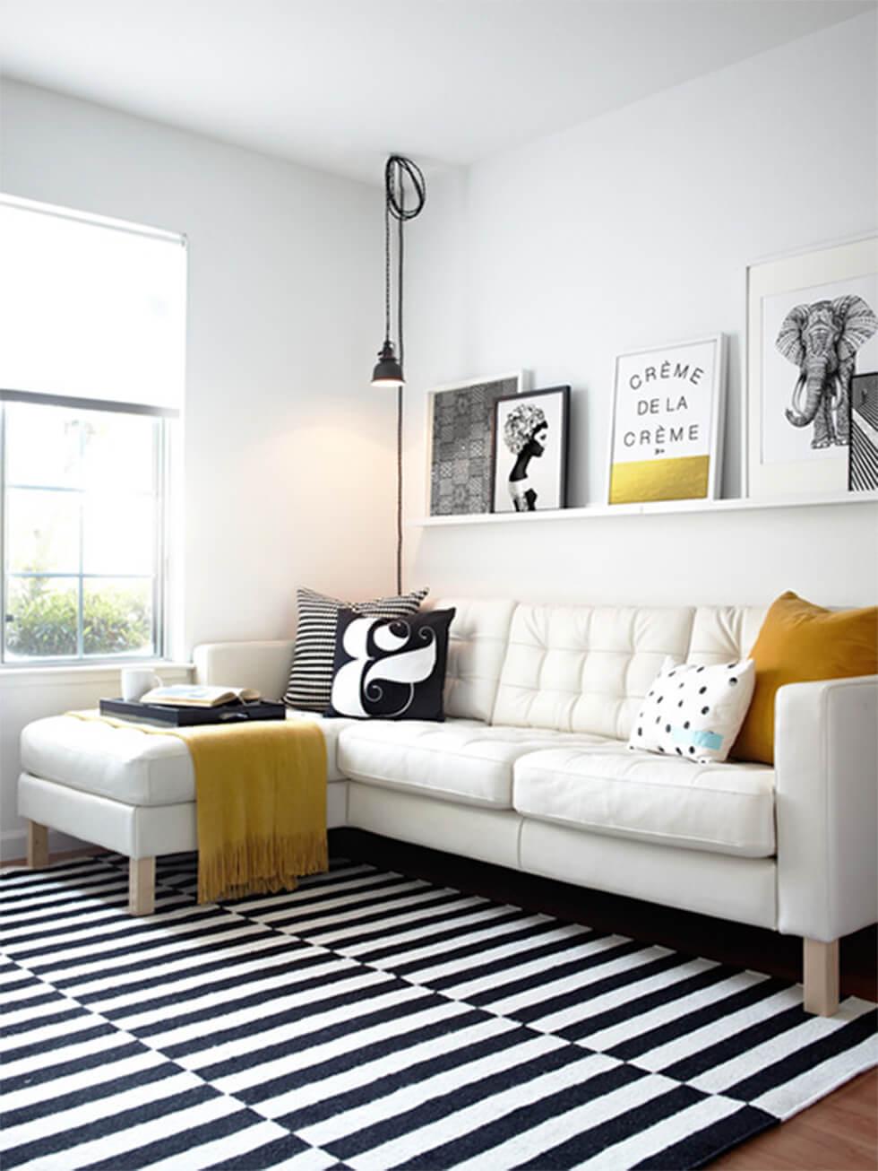 Cosy white corner sofa with a black and white rug in a bright and airy living room.