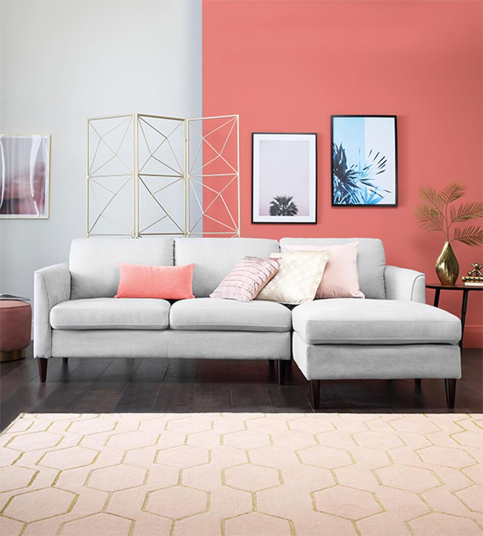 Grey corner sofa against a bright coral and grey feature wall.