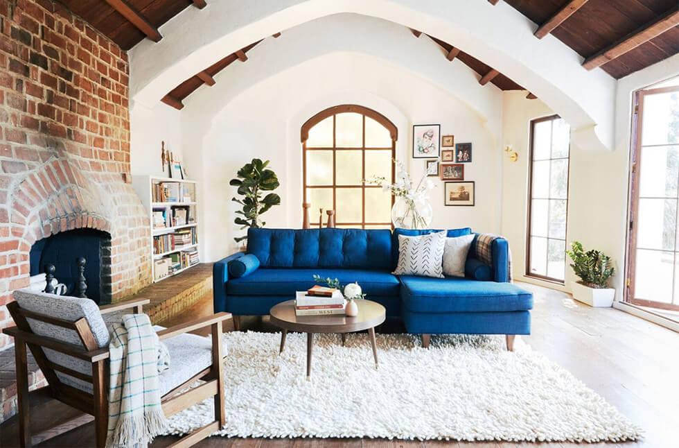 A blue corner sofa with a furry rug in a rustic style living room.