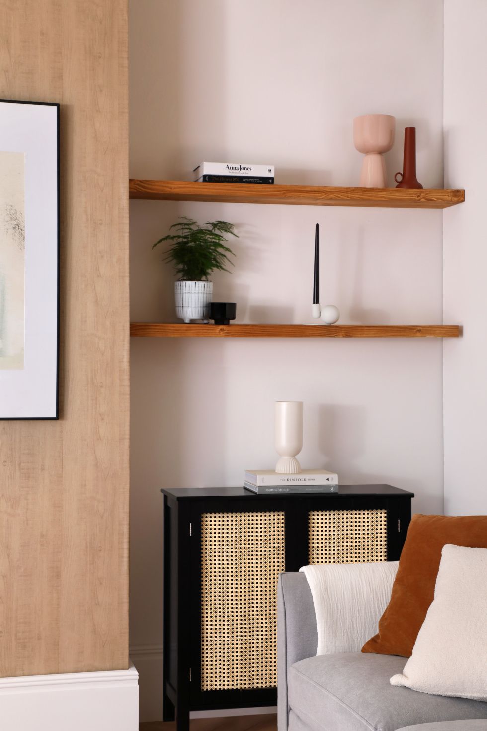 Modern living room with potted plant, vases, books and candle on the wooden shelf