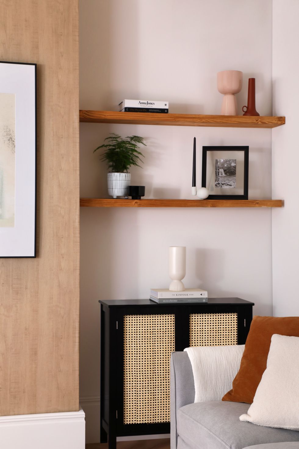 Modern living room with potted plant, vases, books, candle and framed photo on the wooden shelf