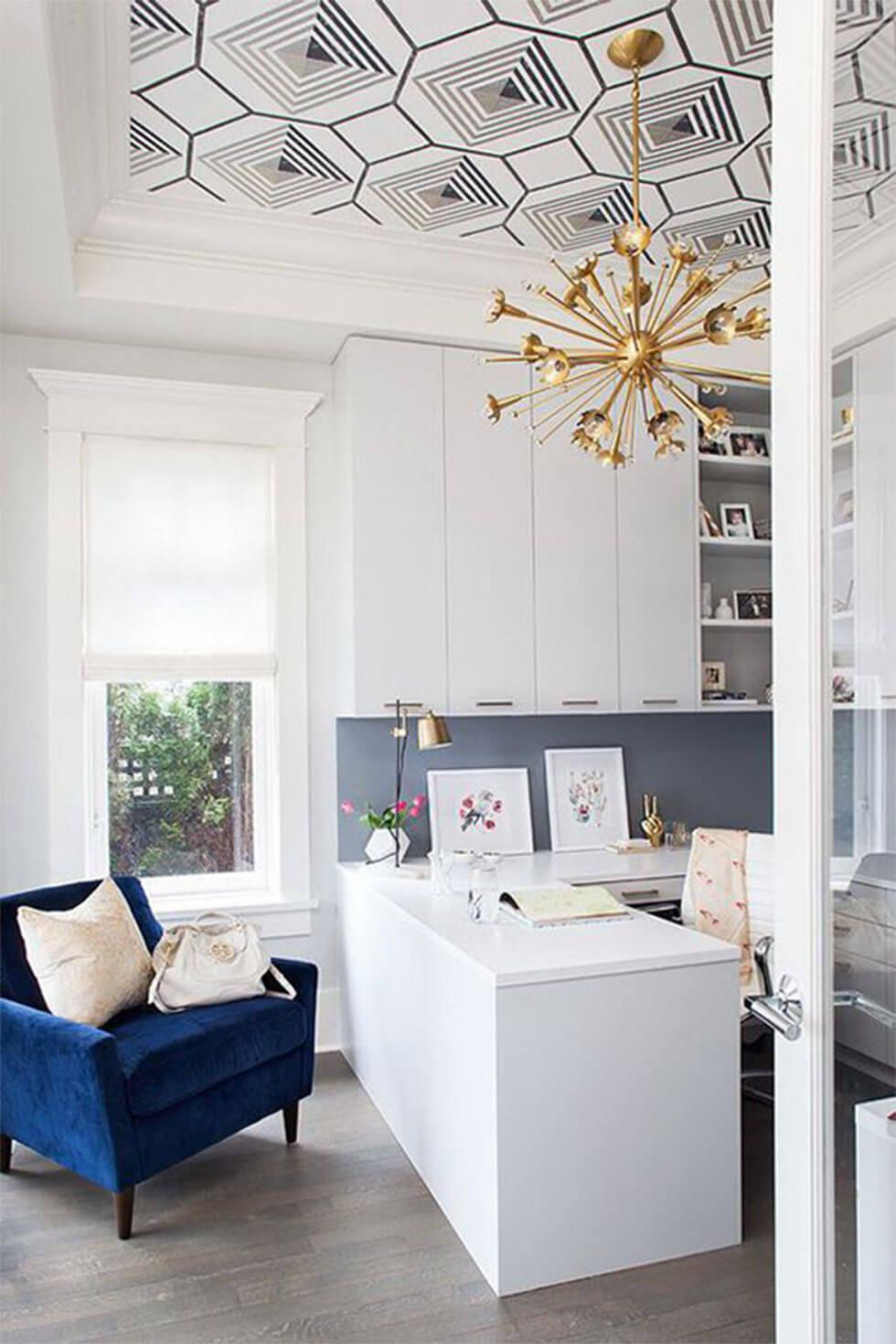 Stylish home office with wallpapered ceiling and classic blue armchair