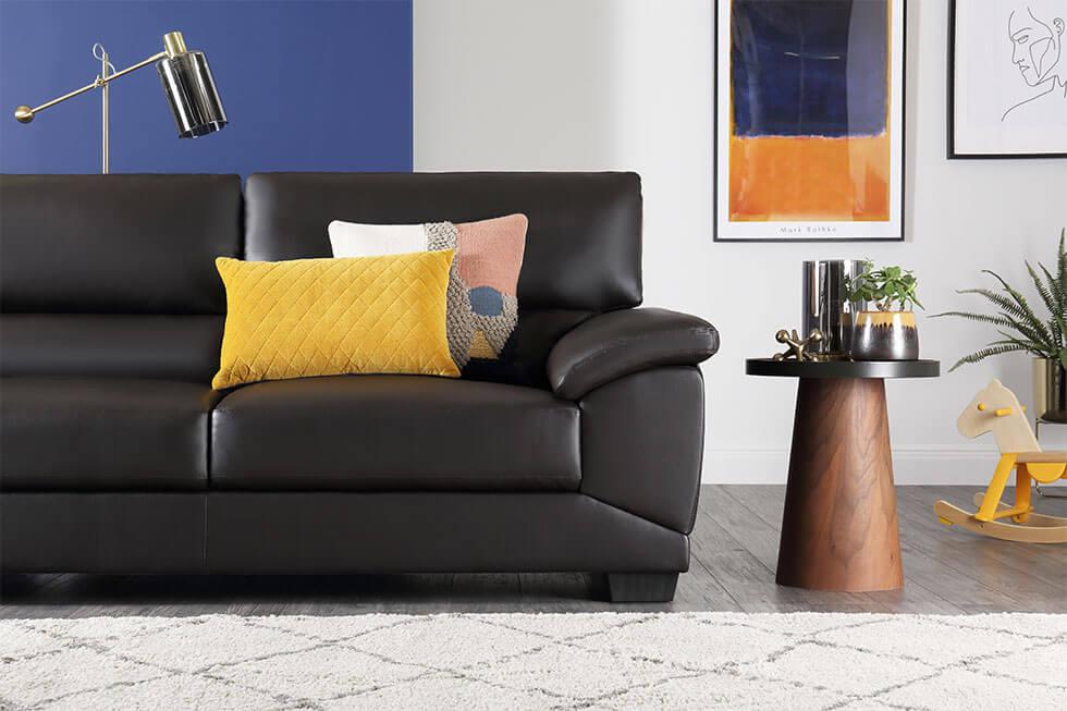 Black leather sofa in a colourful living room with a classic blue wall