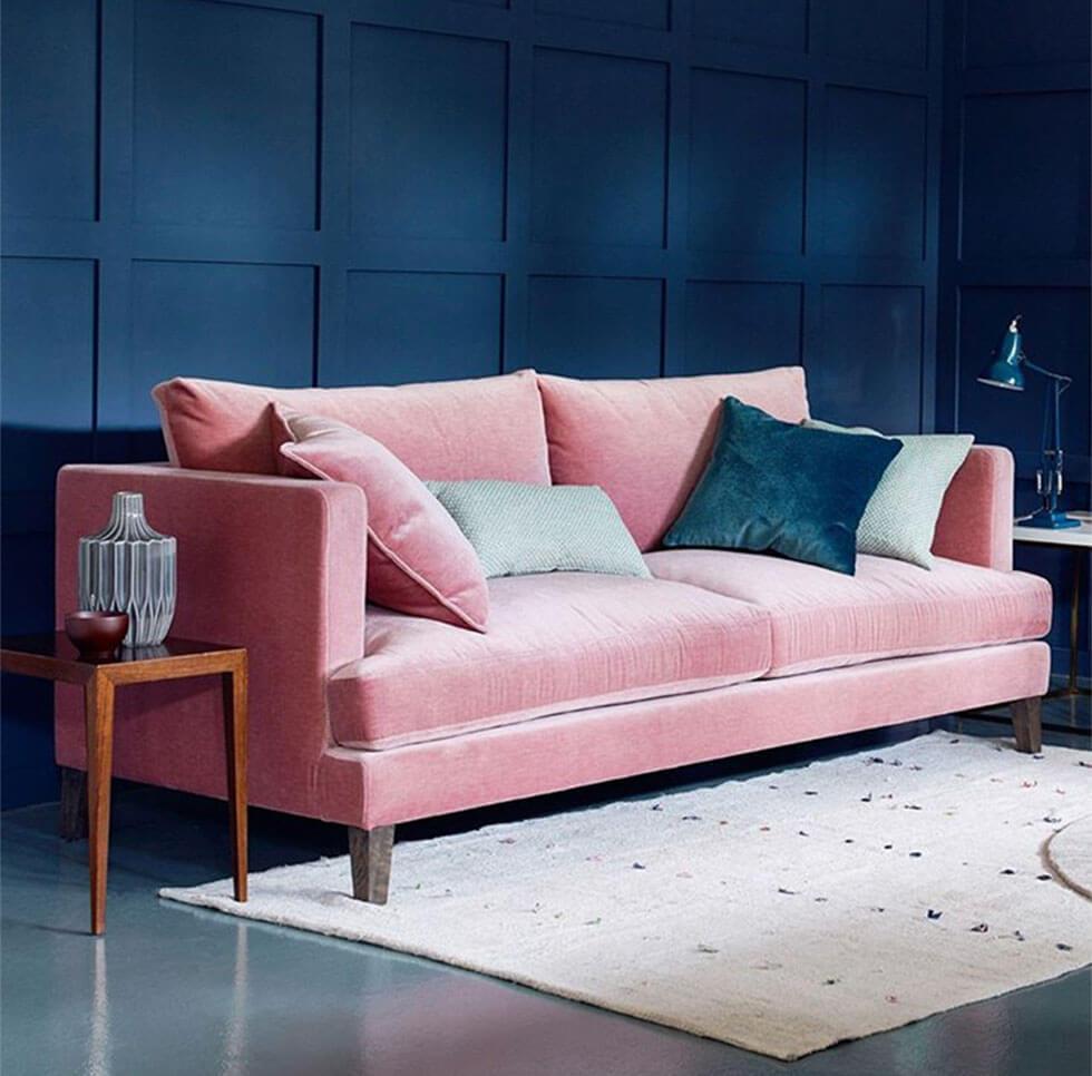 Pink velvet sofa with colourful accessories and striking classic blue walls in the background
