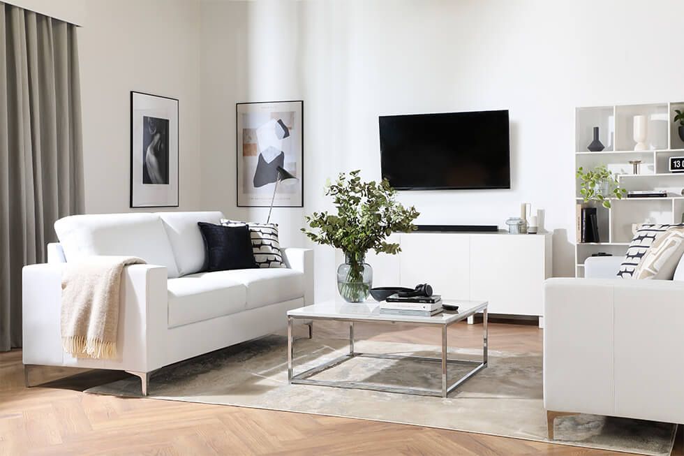 Modern living room featuring two white sofas and a chrome coffee table in the middle