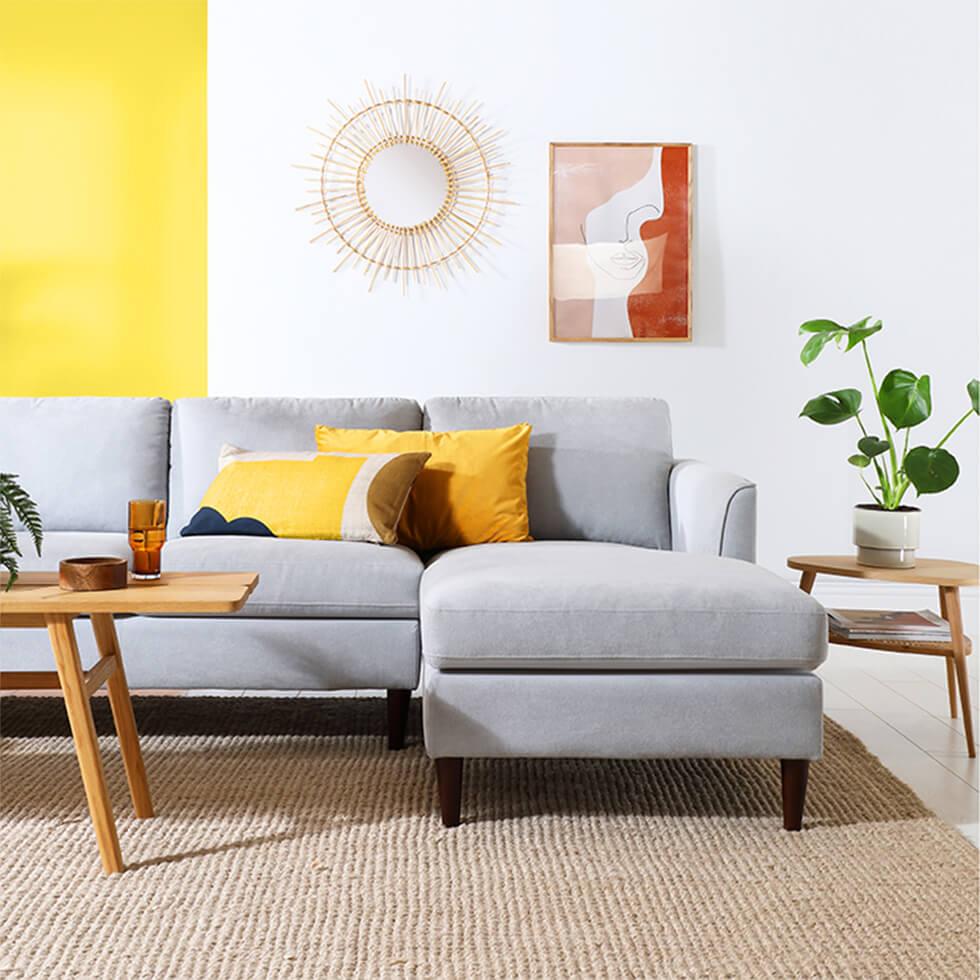 Bright mid-century modern living room with grey fabric sofa, yellow feature wall and sunburst mirror