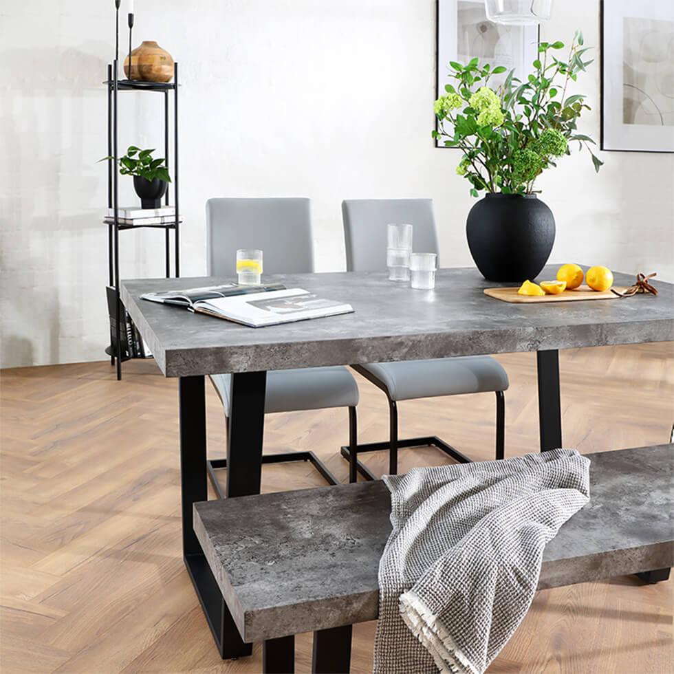 Industrial dining space with concrete table and bench and grey leather chairs