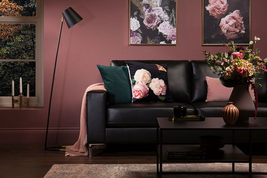 Black leather sofa topped with pink and emerald pillows in a jewel toned living room