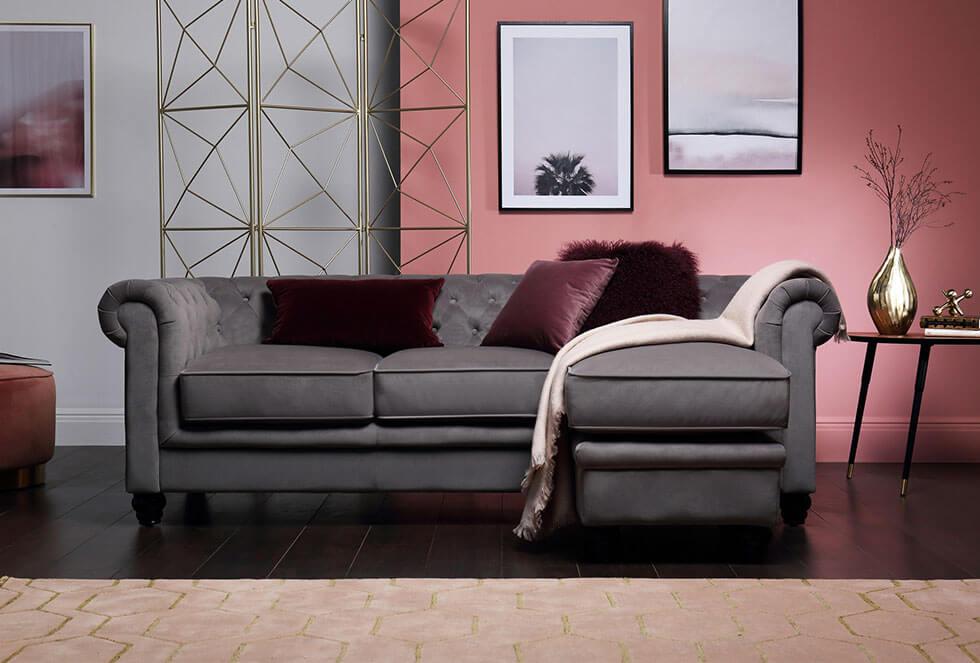 Grey velvet sofa in a dusty pink living room with metallic accessories