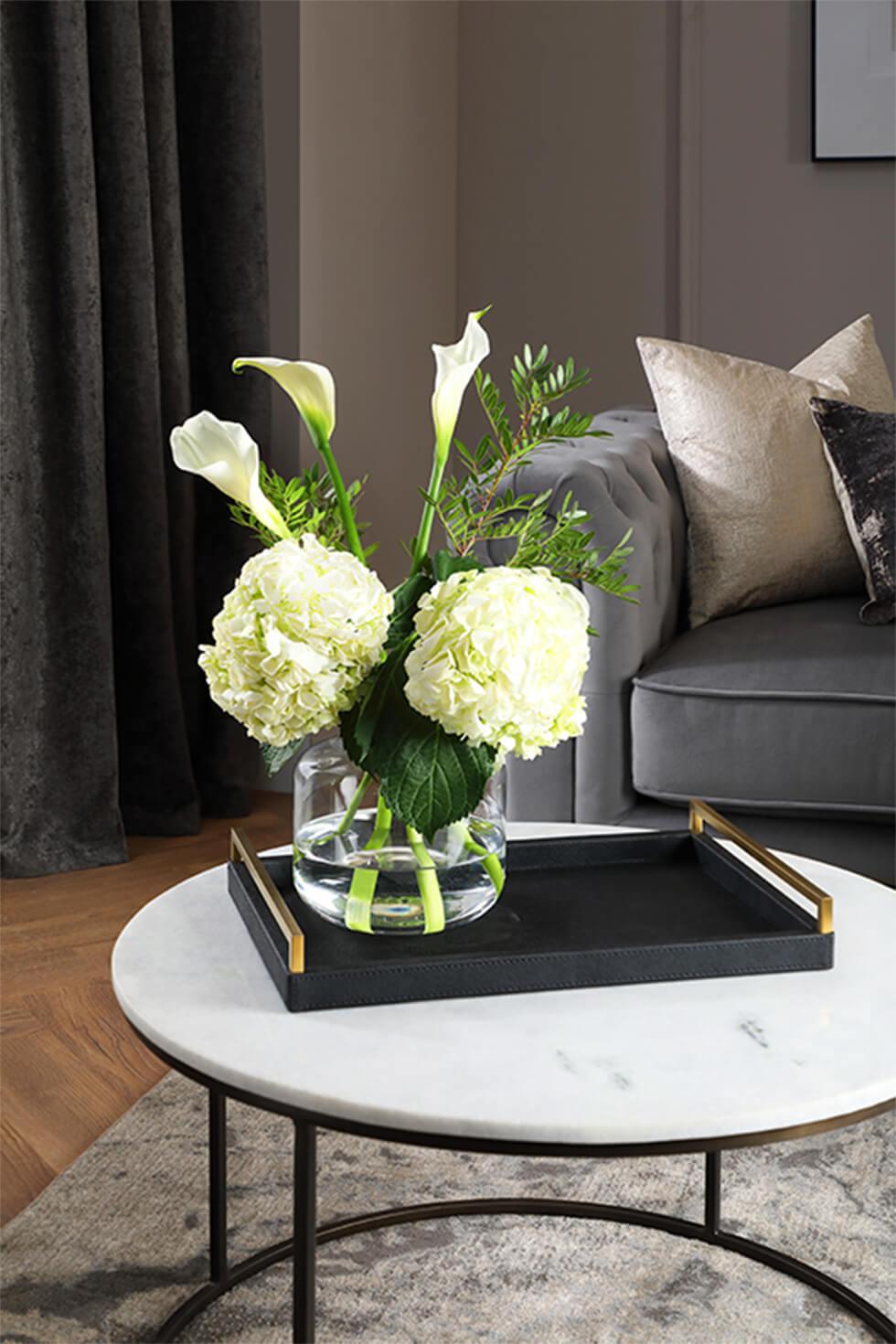Marble coffee table with dark tray, and a vase of flowers