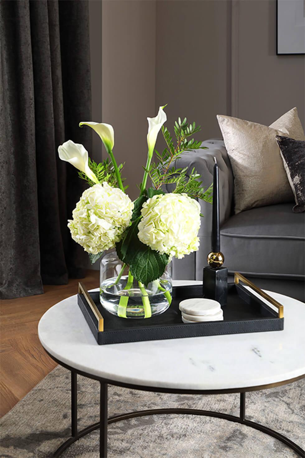 Marble coffee table with dark tray, vase of flowers, candle and marble coasters
