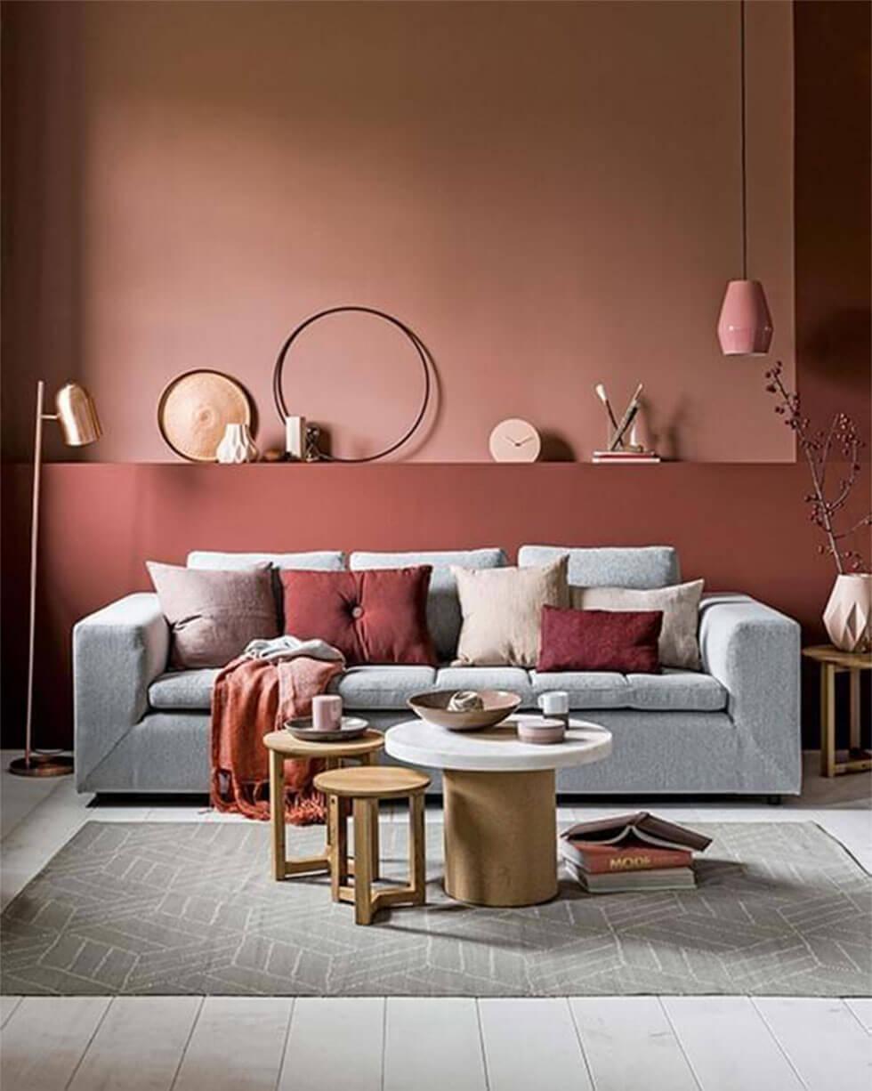 A grey sofa in a Scandinavian style living room with terracotta and burgundy walls.