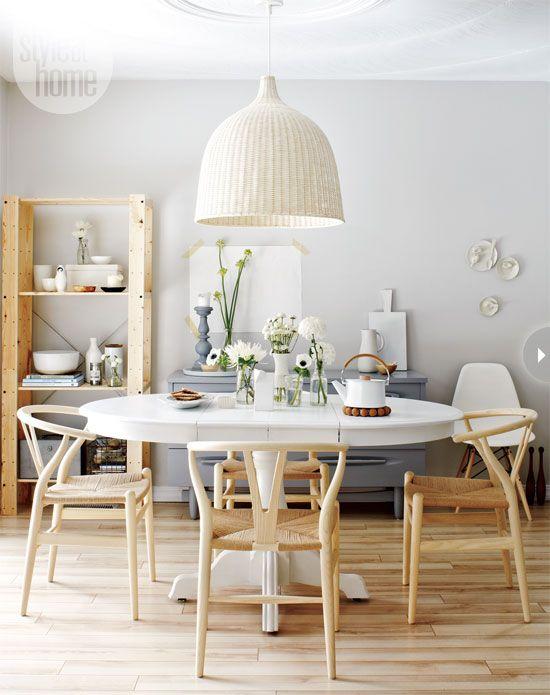 Airy and white dining room with white table, wooden floors and chairs, and white lamp.