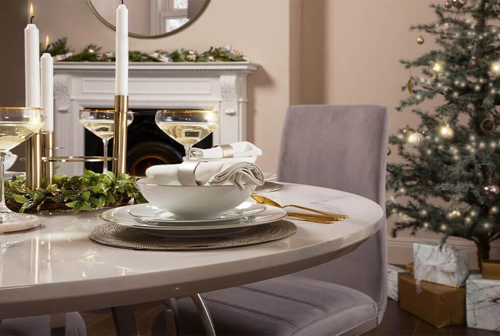 White marble dining table decorated in a glamorous Christmas dinner setting.