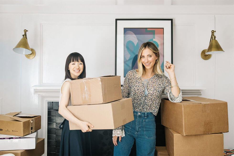Marie Kondo and Emily Schuman holding a pile of boxes