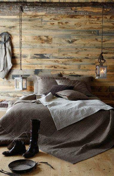 Bedroom with wooden walls and floors, and grey bedding