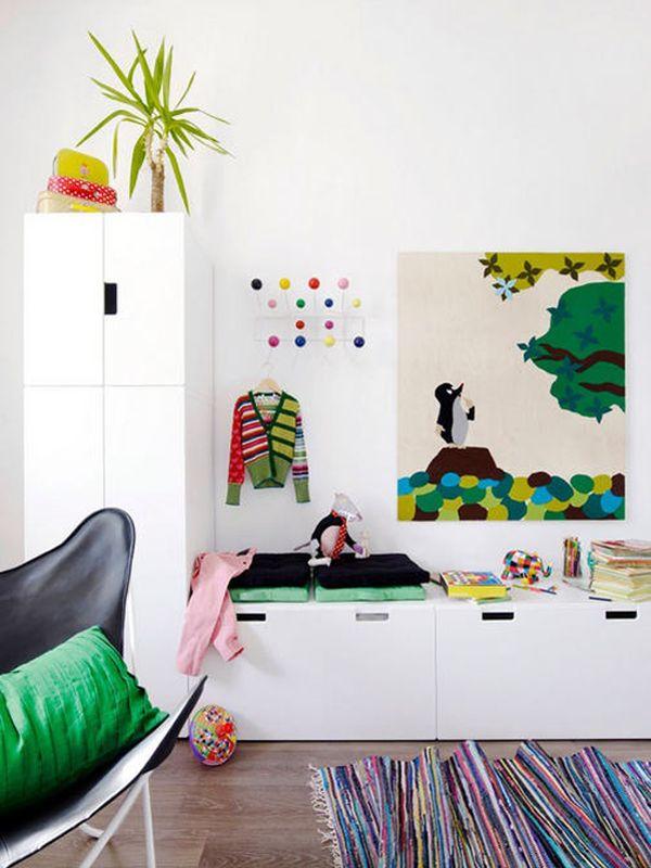 Colourful child’s room with white cabinet and bright art and printed rug.