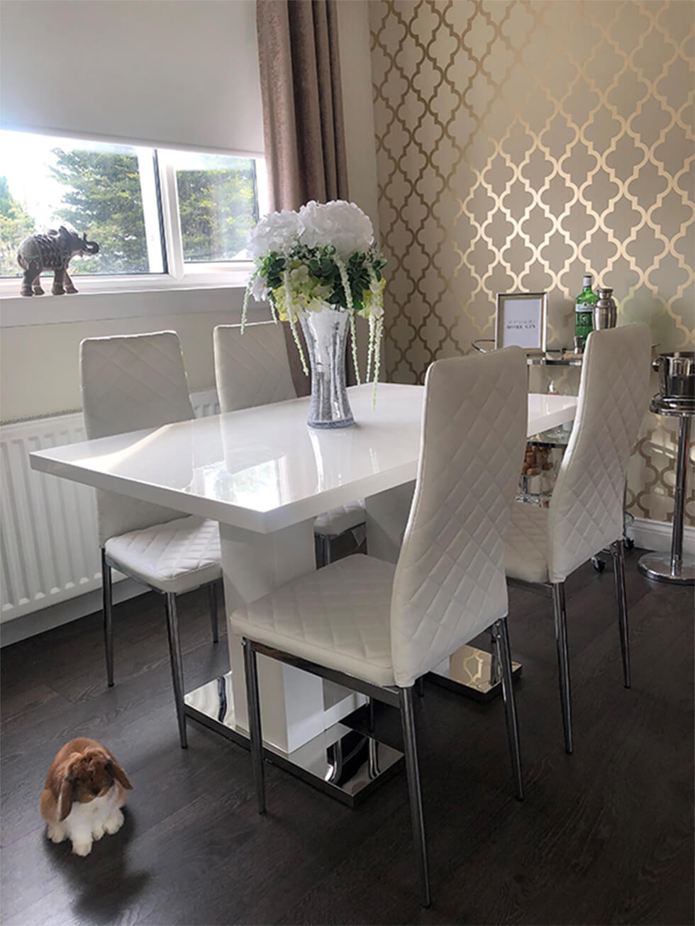 White high gloss dining table with white leather dining chairs in a modern dining room