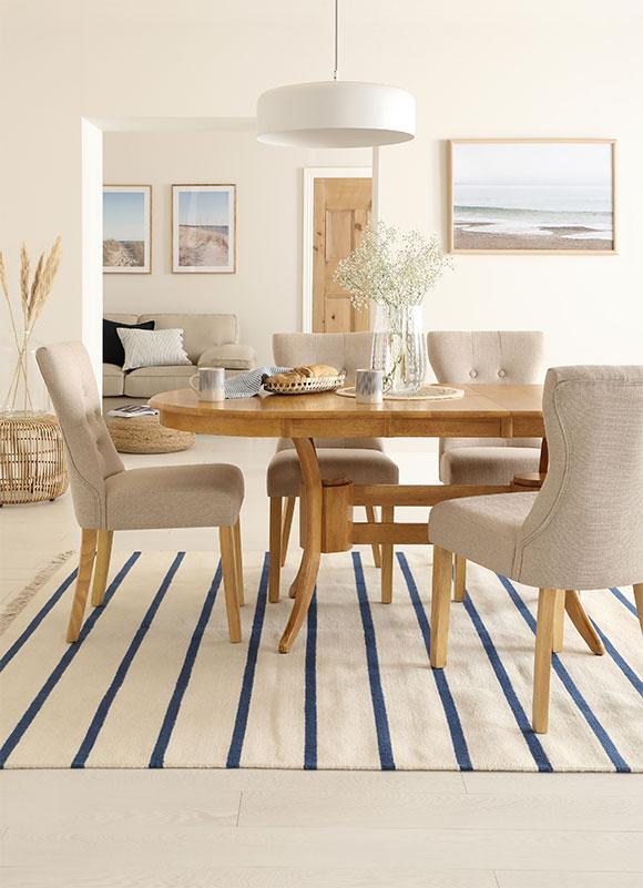 oak dining set with fabric dining chairs and striped rug