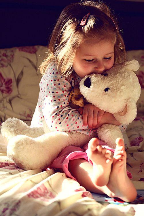 Young girl hugging a white teddy bear.