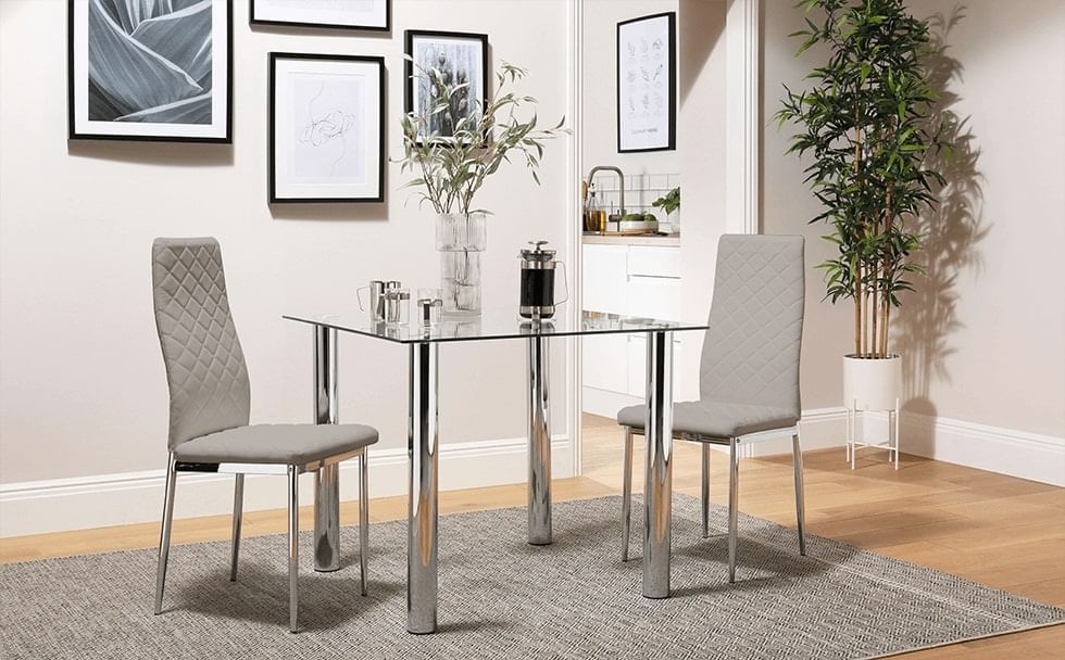 A grey rug under a small glass dining table