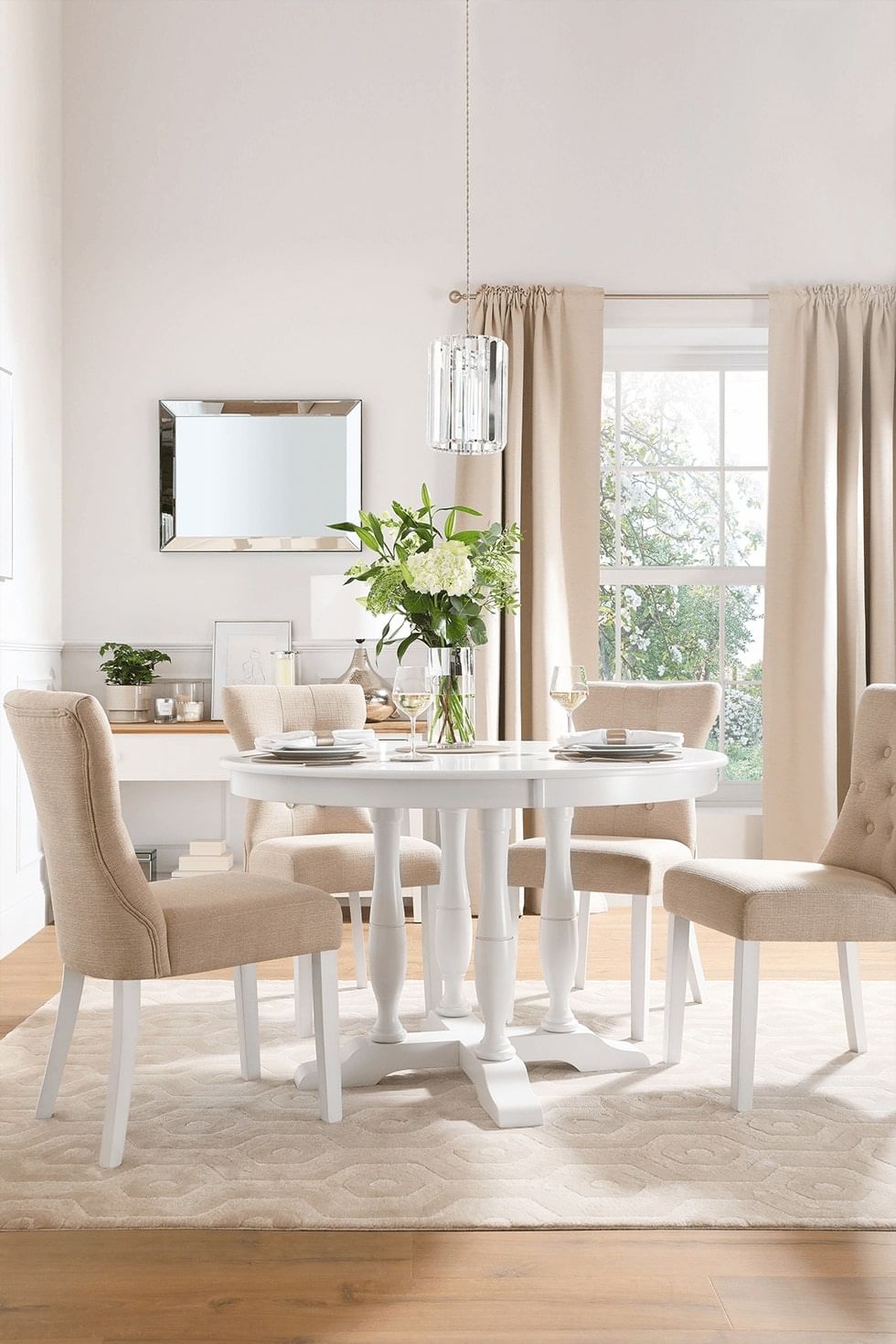 A cream coloured rug under a round, white dining set